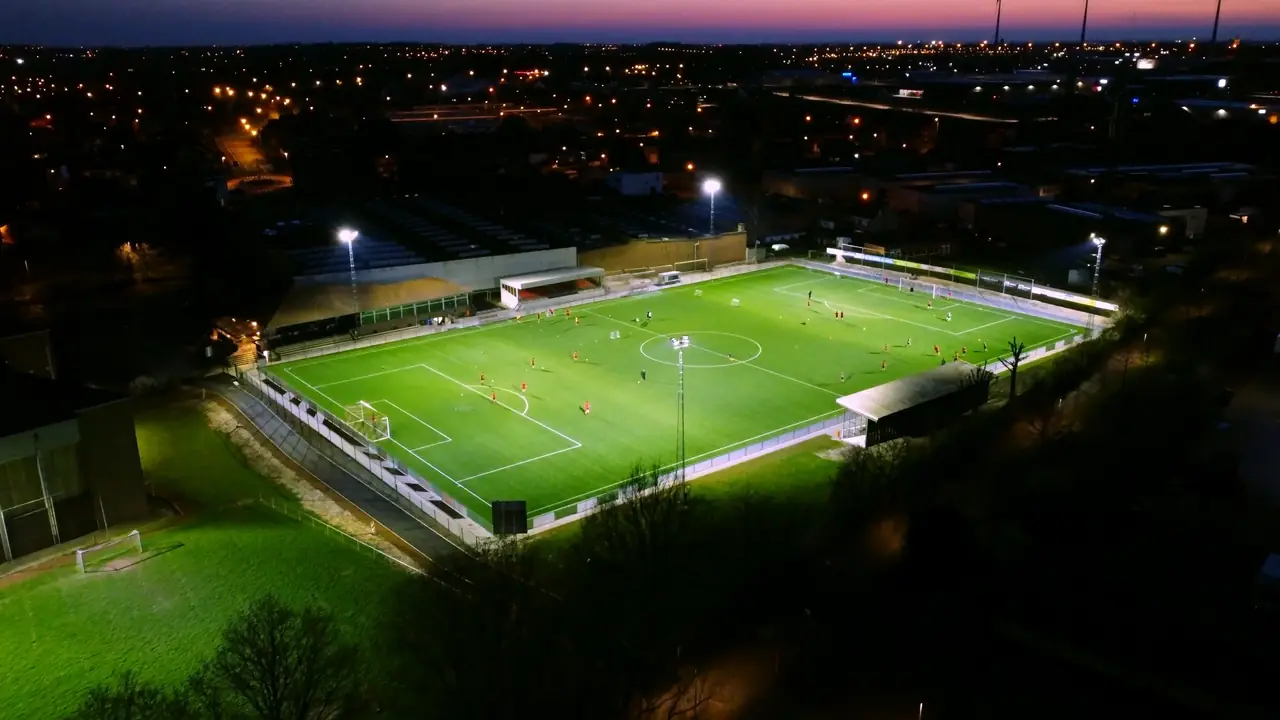 PLATZHALTER: Fußballplatz unter Flutlicht aus der Luft, in der Dämmerung